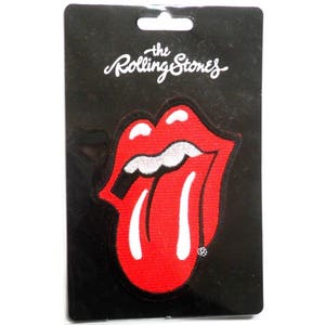 May include: A red and white embroidered patch featuring the Rolling Stones tongue logo. The patch is on a black card with the words "the Rolling Stones" printed in white.