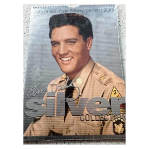 Puede incluir: Calendario oficial de Elvis Presley de 2003. Presenta un retrato sonriente de Elvis Presley con uniforme militar. Las palabras "Silver Collection" se muestran de forma destacada.