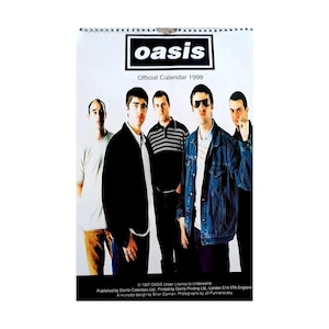 May include: A 1998 Oasis official calendar. The band's name, "oasis", is in a black rectangle with white text. The calendar shows five men. The text "Official Calendar 1998" is below the band's name. The calendar has a white background and a spiral binding at the top.