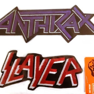 May include: Two iron-on patches, one with the word "ANTHRAX" in purple and black, and the other with the word "SLAYER" in red and black.