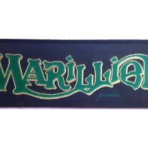 May include: A black and green embroidered patch with the band name "Marillion" in gold lettering. The patch has a copyright symbol and the year "1983" in small white lettering.