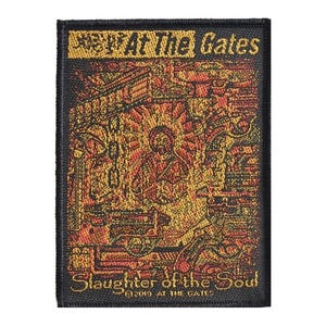 May include: A black woven patch with a gold and orange design. The patch features the text "At The Gates" and "Slaughter of the Soul" with the copyright symbol and the year 2019.