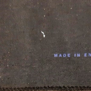 May include: Close-up of a black fabric surface with the text "Made in England" printed in blue.