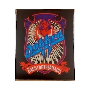 May include: A black and white embroidered patch with a red and blue logo that says "Dokken" and the text "Back for the Attack".