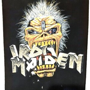 May include: Black and yellow Iron Maiden patch featuring a skull with a robotic eye and the band's name in a 3D font.
