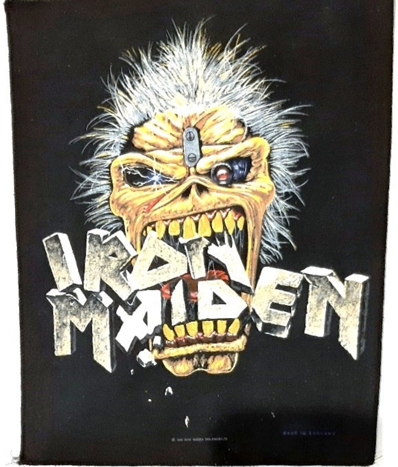 May include: Black and yellow Iron Maiden patch featuring a skull with a robotic eye and the band's name in a 3D font.