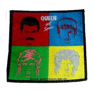 May include: A square fabric patch featuring the band Queen's logo and the album title "Hot Space". The patch is divided into four squares, each showcasing a different band member's face in a different colour: red, blue, green, and yellow. The text "© 1982 Queen Productions Ltd." is at the bottom.