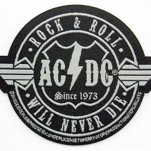 May include: Black and white embroidered patch with the text "Rock & Roll" and "AC/DC" with a lightning bolt logo. The text "Since 1973" and "Will Never Die" are also included.