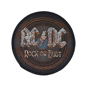 May include: A black and brown circular patch with the text "AC/DC Rock or Bust" in a stylised font. The patch has a textured, worn look, like a vintage record.
