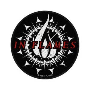 May include: A black and white circular patch with a white flame design in the centre. The flame is surrounded by a circle of spikes. The text "IN FLAMES" is written in red letters above the flame.