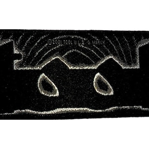 May include: Black and white embroidered patch featuring the word "TOOL" in a stylised font. The patch has a textured background and the text "©2001 TOOL LLC - G. MERCK" is visible at the top.