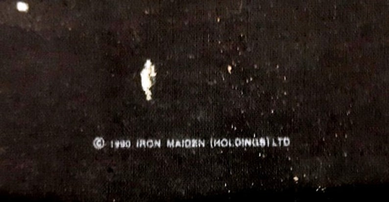 May include: Black and white text on a black background that reads "&copy; 1980 IRON MAIDEN (HOLDINGS) LTD"