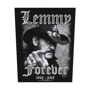 May include: Black and white image of a musician wearing a cowboy hat and pointing at the viewer. The text "Lemmy Forever 1945 - 2015" is printed below the image.