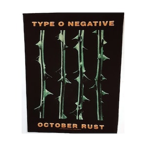 May include: Black patch with the text "TYPE O NEGATIVE" in orange and "OCTOBER RUST" in orange at the bottom.  Three green thorny stems are in the center of the patch.