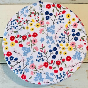 Reusable bowl covers in "Wildflower" print: a vibrant floral pattern on a white background. The design features red, blue, yellow, and pink flowers with green stems and leaves. The flowers are scattered across the surface, creating a cheerful and colorful look.