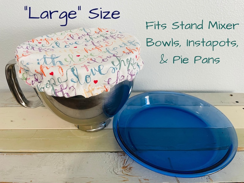 Reusable "Large" sized fabric bowl cover in "Names of Jesus" print: white fabric with the words "love", "hope", and "faith" in various colors.  The cover is on a stainless steel stand mixer bowl. A blue pie pan sits next to the bowl. Text on the image reads "Large" Size and "Fits Stand Mixer Bowls, Instapots, & Pie Pans."