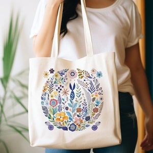 May include: A white canvas tote bag with a colorful floral design. The flowers are arranged in a circle and include pink, blue, yellow, and green colors.