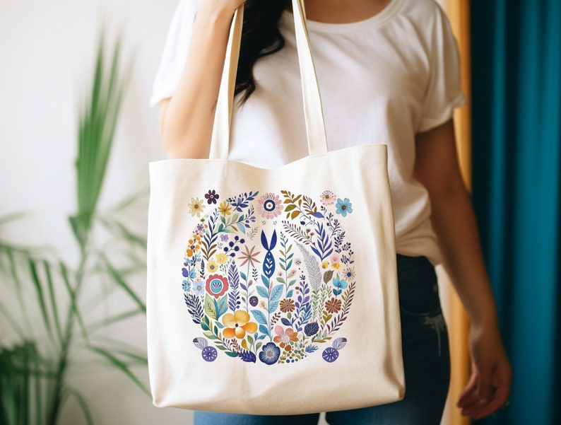 May include: A white canvas tote bag with a colorful floral design. The flowers are arranged in a circle and include pink, blue, yellow, and green colors.