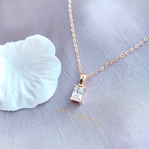 Op de afbeelding: Een gouden ketting met een vierkante hanger met een heldere zirkonia-steen.