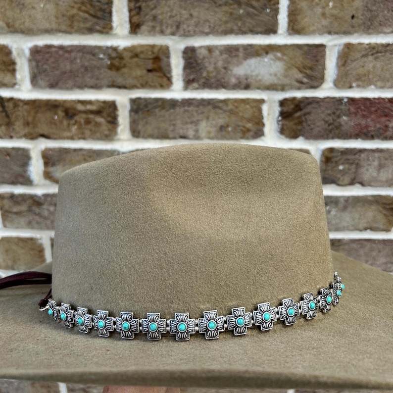 May include: A light brown felt cowboy hat with a silver and turquoise beaded band.