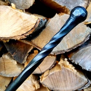 May include: A black metal fireplace poker with a twisted handle and a rounded end.