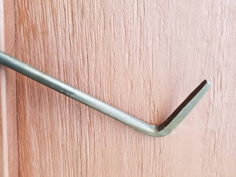May include: A close-up of a metal pry bar with a curved end. The bar is silver in color and has a slightly textured surface.
