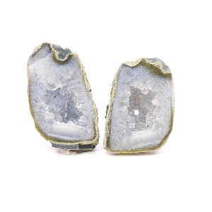 May include: Two halves of a geode with a white crystal interior and a brown, green, and gray exterior.