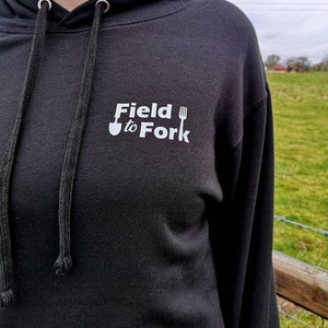 May include: Black hooded sweatshirt with a white logo that says "Field to Fork" with a shovel and fork graphic.