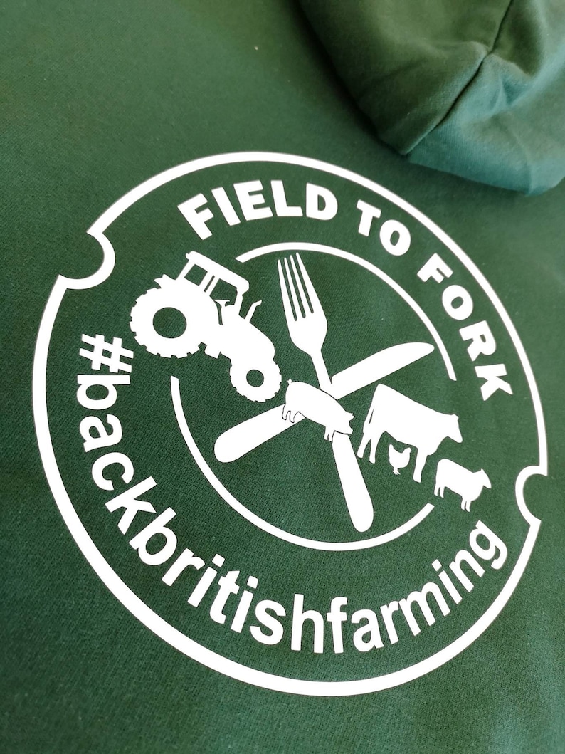 May include: White graphic on a green hoodie with a circle containing the text "FIELD TO FORK #backbritishfarming" and a tractor, fork, knife, pig, cow, chicken, and sheep.