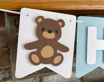 May include: White banner with a brown teddy bear, blue banner with the letter H, and a brown banner.