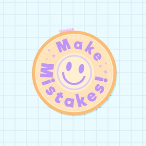 May include: A circular sticker featuring the phrase "Make Mistakes" in purple, encircling a smiling face. The sticker has an orange border and a pale yellow centre, set against a light blue grid background.