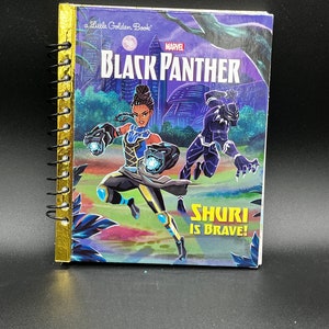 Może przedstawiać: Spiralny notatnik z okładką z "Little Golden Book" zatytułowanego "Black Panther" z logo Marvel. Okładka przedstawia Shuri i Black Panther w kolorowej scenie. Widoczny jest również tekst "Shuri is Brave!"