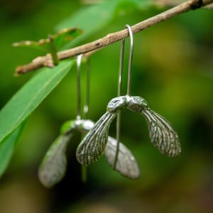 Pendientes largos colgantes florales con diseño de semillas de arce en plata de ley.