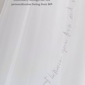 K&ouml;nnte beinhalten: Ein transparenter wei&szlig;er Brautschleier mit zarter wei&szlig;er Schreibschrift-Stickerei entlang der Kante. Der Stoff ist durchscheinend und leicht. Der Text lautet: Choose to add custom hand stitched embroidery through our veil personalization listing from $69 und And he put between you, love and mercy.