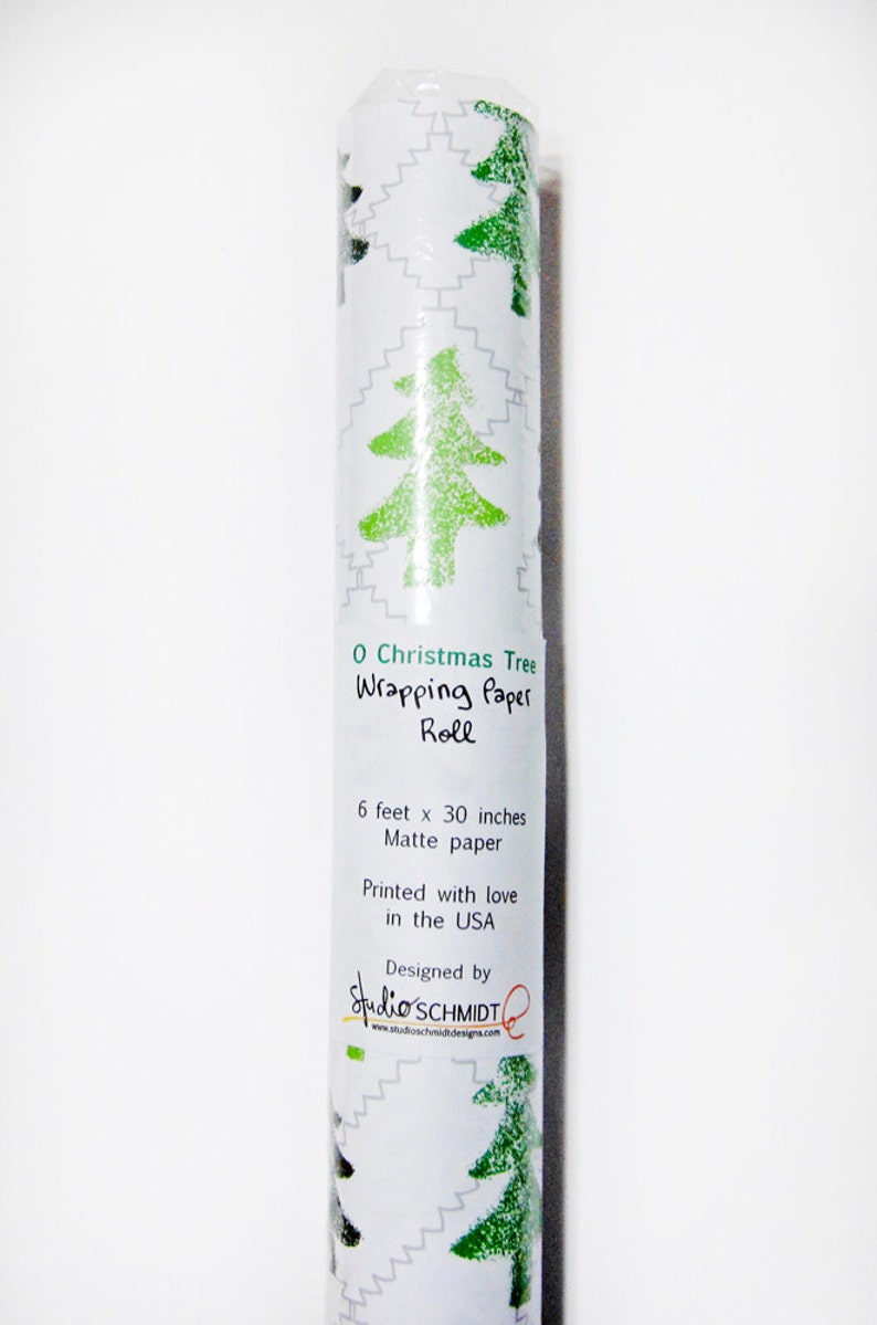 May include: A roll of green and white Christmas wrapping paper with a green stylized Christmas tree design. The paper is 6 feet by 30 inches and is printed with love in the USA. The label also says "O Christmas Tree Wrapping Paper Roll" and "Designed by Studio'SCHMIDT".