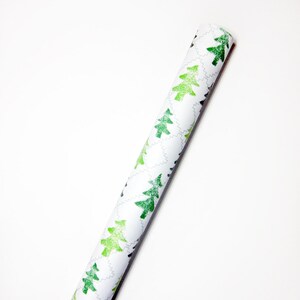 May include: A roll of white wrapping paper with a repeating pattern of green Christmas trees.