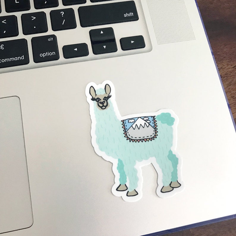 Puede incluir: Una pegatina de llama azul claro con un dise&ntilde;o de monta&ntilde;a en la espalda. La llama tiene ojos negros y pesta&ntilde;as, y una nariz marr&oacute;n.