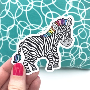 May include: A black and white zebra with a rainbow mane. The zebra is standing on all fours and has a happy expression on its face.
