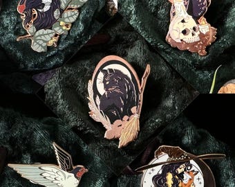 Puede incluir: Conjunto de cinco pines de esmalte que representan una cabra negra con cuernos, un gato negro en una luna creciente, un cuervo negro con una calavera y velas, una golondrina en vuelo y una bruja con un zorro en una luna creciente. Los pines son todos de color dorado y tienen detalles en blanco y negro.