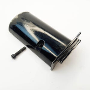 May include: Black metal part with a rectangular base and a curved top. A small black screw is included.