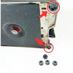 May include: Close-up of a black sewing machine with five small black screws removed. The screws are visible in the lower right corner of the image.