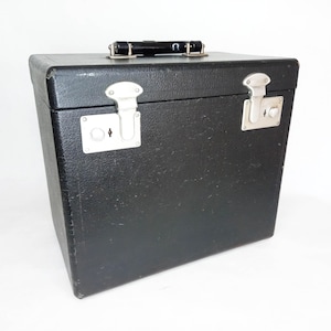 May include: A black vintage carrying case with silver metal latches and a black handle. The case has a textured surface.