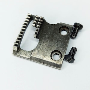 May include: A silver metal sewing machine foot with a toothed edge and two holes. Two black screws are next to the foot.