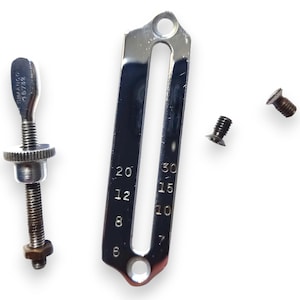 May include: A collection of vintage sewing machine parts, including a shiny metal gauge with numbered markings, a threaded rod with a knob, and several small screws. The gauge has the numbers 6, 8, 10, 12, 15, 20, and 30.