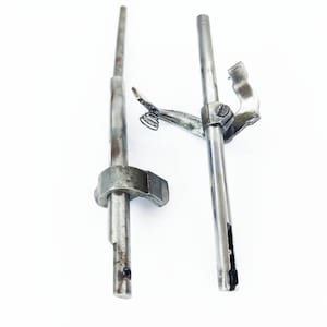 May include: Two silver metal sewing machine parts with a spring attached to one of the parts.