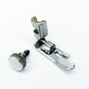 May include: A silver sewing machine foot with a screw and a knob. The foot has a curved shape and a small opening in the center.