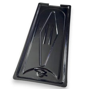 May include: A black, rectangular plastic container with a glossy finish. The container features a raised, stylized fork design in the centre and a small circular indentation at one end. The shape is slightly trapezoidal.