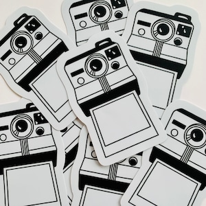 May include: A set of ten black and white instant camera stickers. Each sticker features a vintage-style instant camera with a blank film frame.