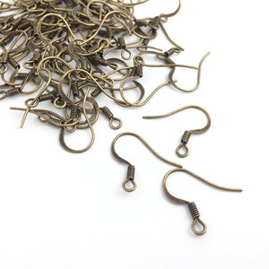 May include: A pile of gold-toned earring hooks, a type of jewelry finding, on a white background.