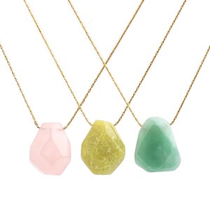 May include: Three necklaces with gold chains and faceted gemstone pendants. The pendants are in shades of pink, yellow-green, and light green. The gemstones have irregular, organic shapes, and the chains are delicate.